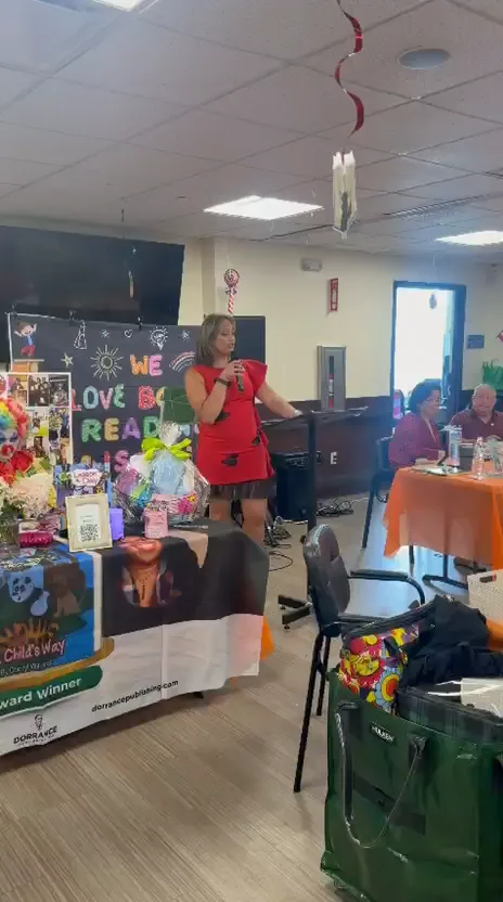 Olga speaking beside a reading celebration display at Exceed